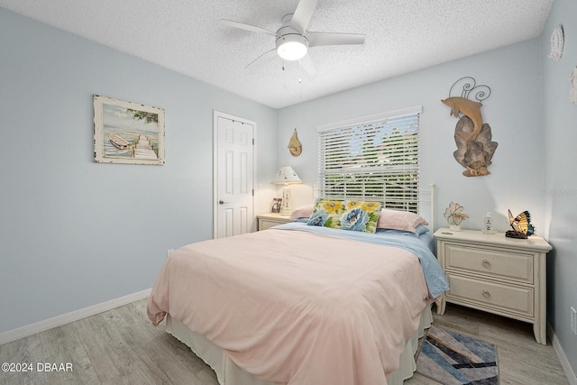 bedroom featuring ceiling fan, light hardwood / wood-style flooring, and a textured ceiling