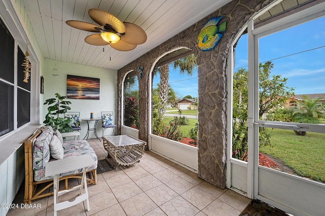 sunroom / solarium with ceiling fan, a healthy amount of sunlight, and wood ceiling