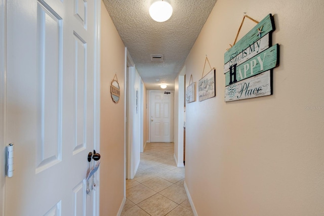 hallway featuring light tile patterned flooring and a textured ceiling