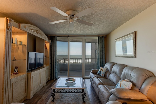 living room featuring ceiling fan, dark hardwood / wood-style flooring, and a textured ceiling