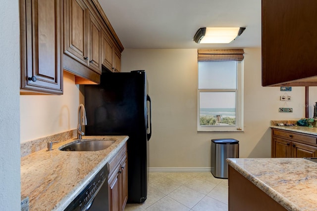 kitchen featuring light stone countertops, sink, dishwasher, and light tile patterned floors