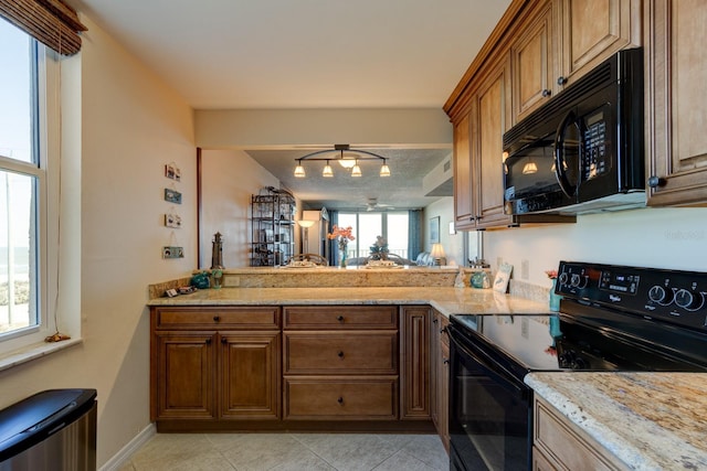 kitchen featuring light stone counters, light tile patterned floors, and black appliances