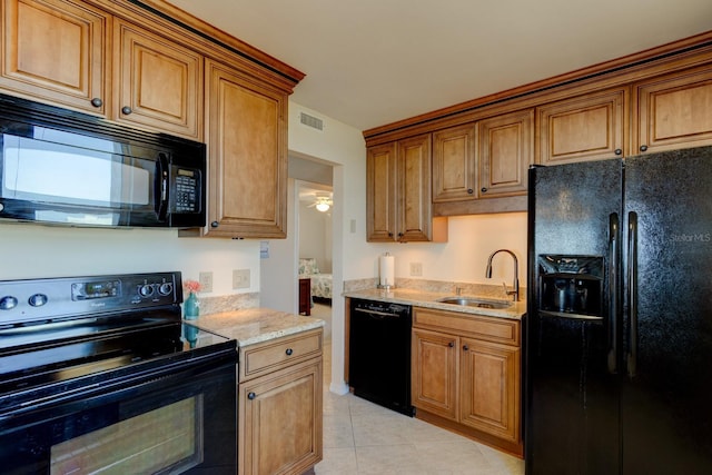 kitchen with light tile patterned flooring, light stone countertops, sink, and black appliances