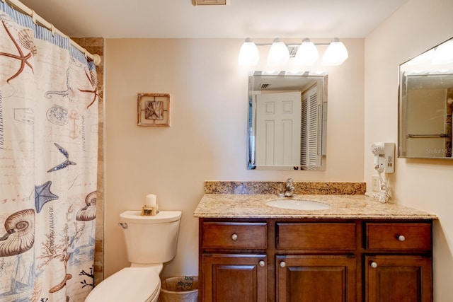 bathroom featuring vanity, walk in shower, and toilet