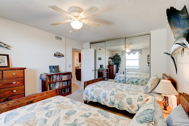 bedroom featuring ceiling fan, light colored carpet, a closet, and a textured ceiling