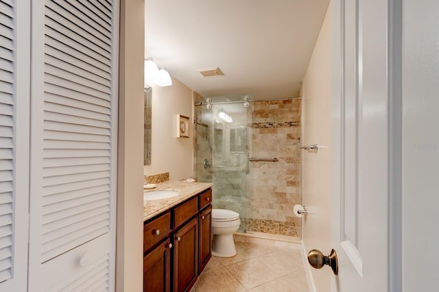 bathroom with vanity, a tile shower, tile patterned floors, and toilet