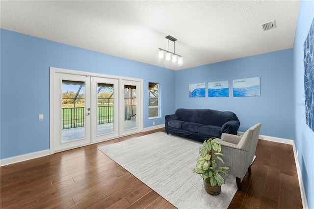 living room with french doors, dark hardwood / wood-style floors, and a textured ceiling