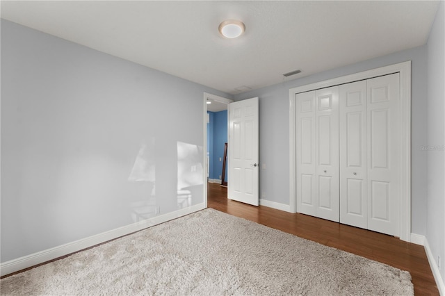 unfurnished bedroom with dark hardwood / wood-style floors and a closet