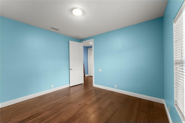 empty room featuring a textured ceiling and dark hardwood / wood-style flooring