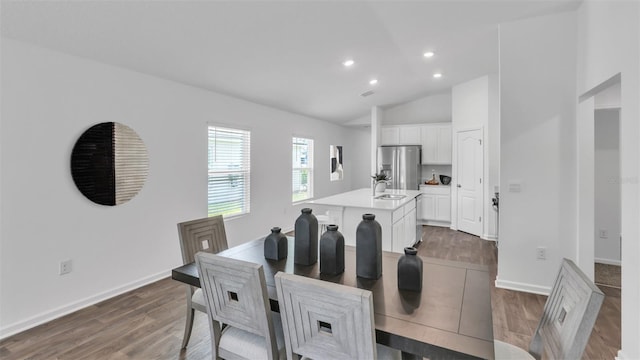 dining space featuring vaulted ceiling, sink, and hardwood / wood-style floors