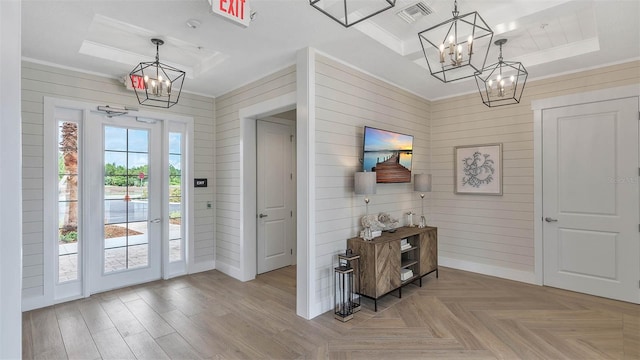 doorway featuring a raised ceiling, light parquet floors, and a notable chandelier