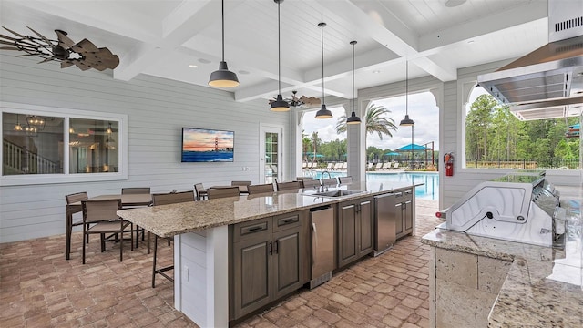 kitchen with refrigerator, sink, a kitchen bar, hanging light fixtures, and dark brown cabinets