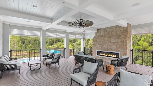 sunroom / solarium featuring beamed ceiling, ceiling fan, coffered ceiling, and a fireplace