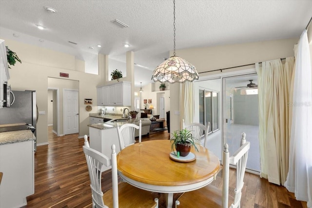 dining room featuring vaulted ceiling, dark hardwood / wood-style floors, sink, ceiling fan, and a textured ceiling