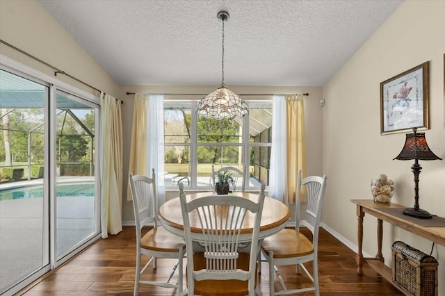 dining space featuring dark wood-type flooring and a textured ceiling