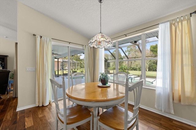 dining space featuring lofted ceiling, dark hardwood / wood-style floors, and a textured ceiling