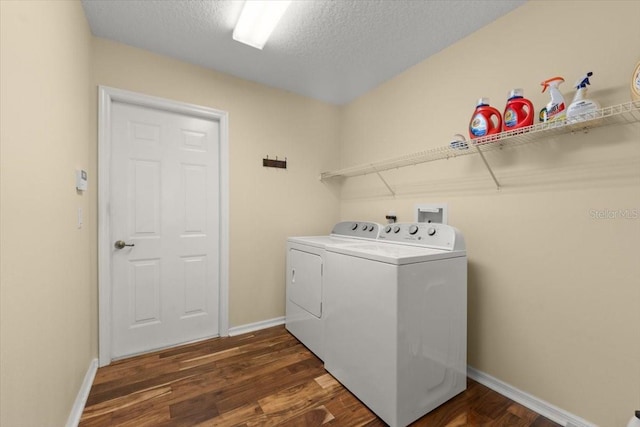 clothes washing area with dark wood-type flooring, washing machine and dryer, and a textured ceiling