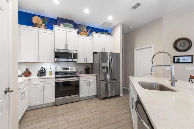 kitchen featuring light stone counters, sink, stainless steel appliances, and white cabinets