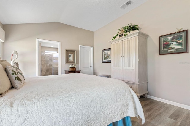 bedroom featuring vaulted ceiling, wood-type flooring, and ensuite bath