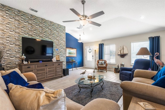 living room featuring ceiling fan, vaulted ceiling, a textured ceiling, and light hardwood / wood-style flooring