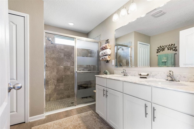 bathroom featuring hardwood / wood-style flooring, vanity, a textured ceiling, and walk in shower