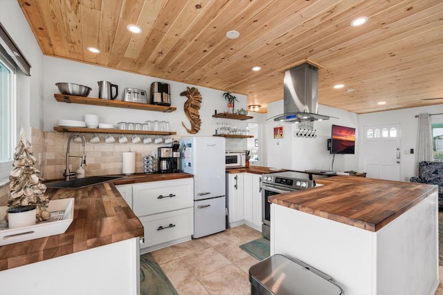 kitchen featuring island range hood, butcher block counters, sink, white cabinets, and white appliances