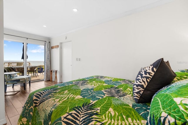 bedroom featuring a water view, crown molding, light hardwood / wood-style flooring, and access to outside