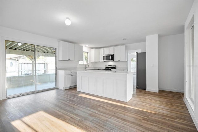 kitchen with a kitchen island, light hardwood / wood-style floors, white cabinets, and appliances with stainless steel finishes