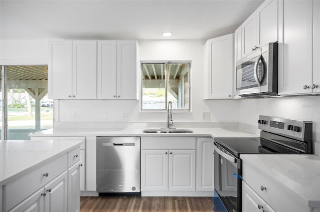 kitchen featuring white cabinetry, sink, light stone counters, stainless steel appliances, and a healthy amount of sunlight