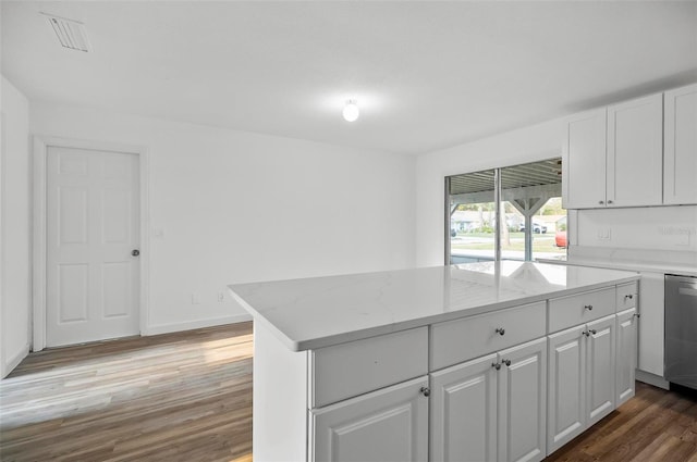 kitchen with dark wood-type flooring, white cabinetry, a center island, light stone counters, and stainless steel dishwasher