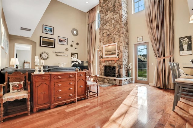 sitting room featuring light wood-type flooring, a fireplace, and a towering ceiling