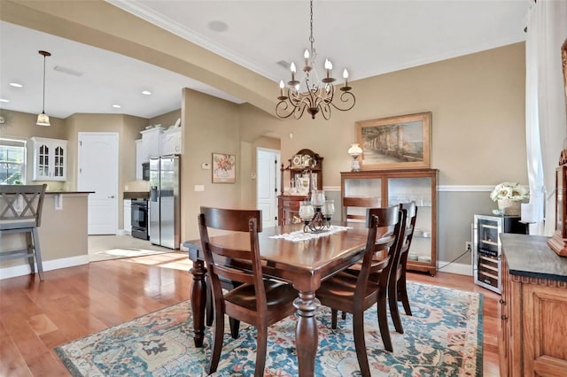 dining space with crown molding, beverage cooler, a chandelier, and light hardwood / wood-style flooring