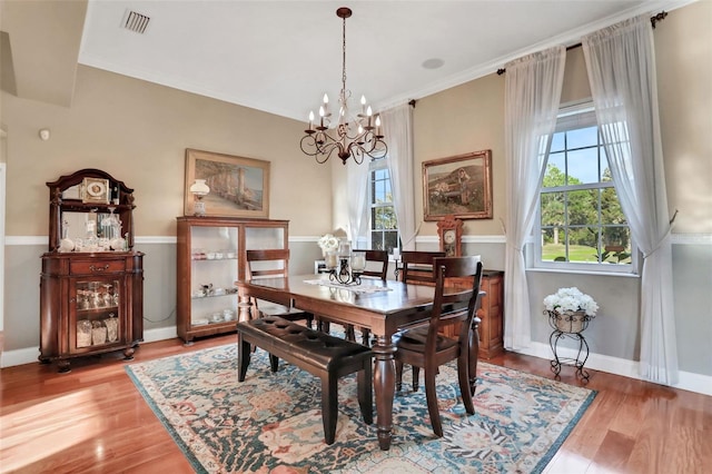 dining area with hardwood / wood-style floors, a wealth of natural light, and a notable chandelier