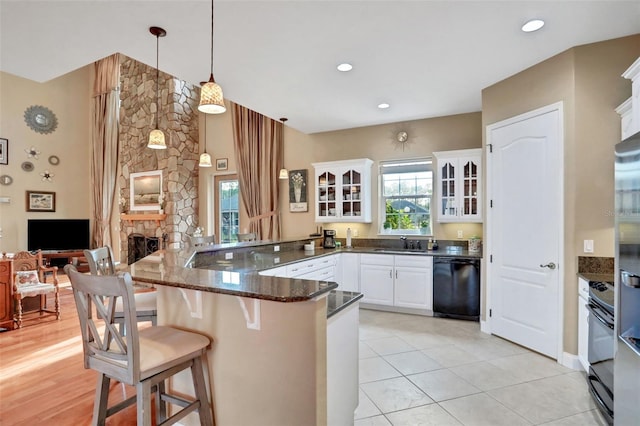 kitchen featuring decorative light fixtures, black dishwasher, white cabinets, a kitchen breakfast bar, and kitchen peninsula