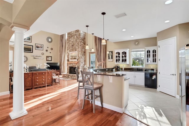 kitchen featuring white cabinetry, hanging light fixtures, black dishwasher, and ornate columns