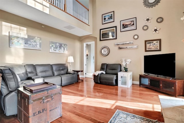 living room featuring a towering ceiling and wood-type flooring