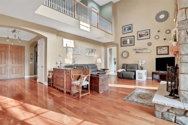 living room with ceiling fan, a towering ceiling, and light wood-type flooring