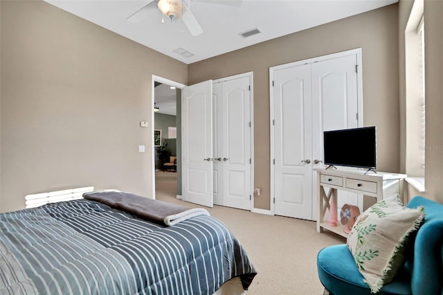 carpeted bedroom with two closets and ceiling fan