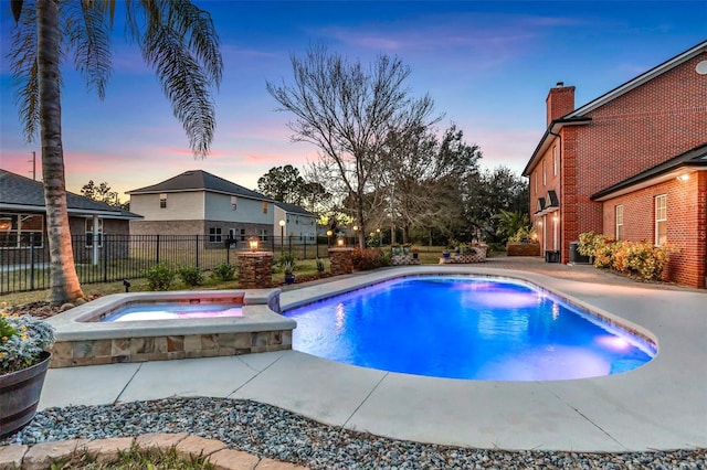 pool at dusk with an in ground hot tub