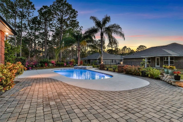 pool at dusk with a patio area