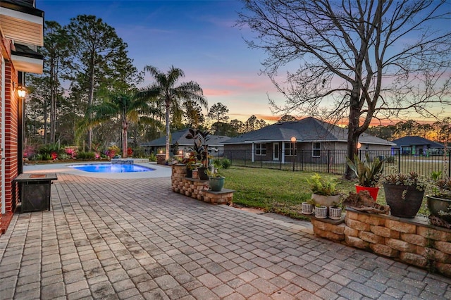 patio terrace at dusk with a fenced in pool and a lawn