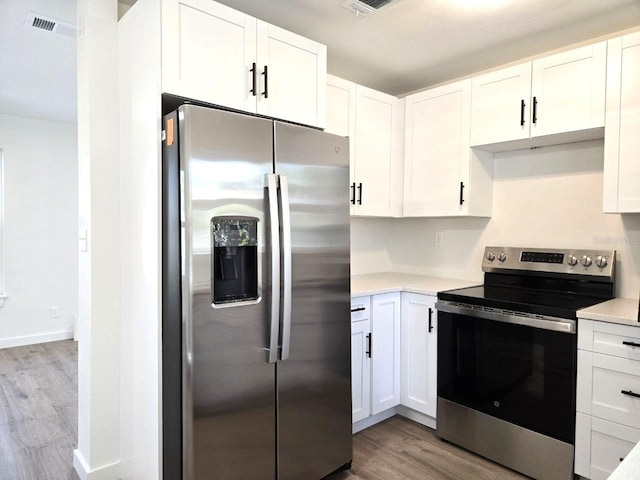 kitchen with appliances with stainless steel finishes, light hardwood / wood-style floors, and white cabinets