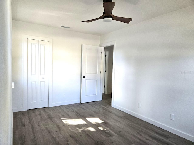 unfurnished bedroom featuring dark wood-type flooring, ceiling fan, and a closet