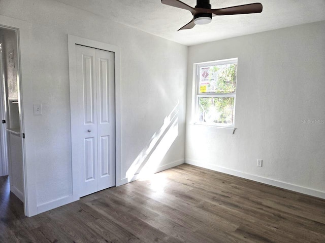 unfurnished bedroom featuring dark wood-type flooring, ceiling fan, and a closet