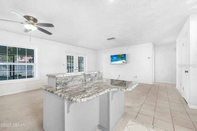 kitchen with french doors, ceiling fan, light tile patterned floors, and a wealth of natural light