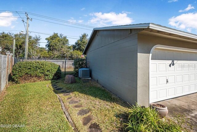 view of side of property featuring central AC unit, a yard, and a garage