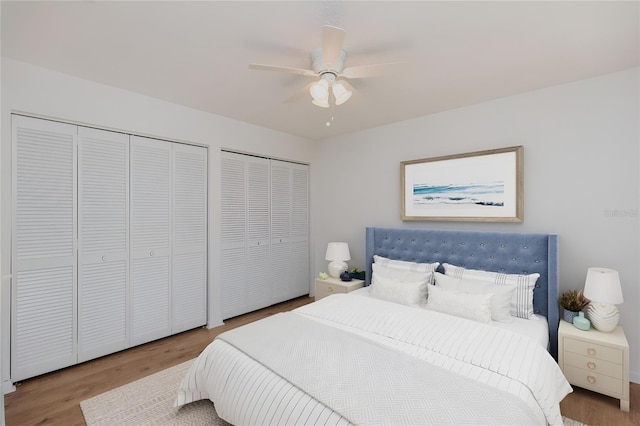 bedroom with hardwood / wood-style flooring, two closets, and ceiling fan