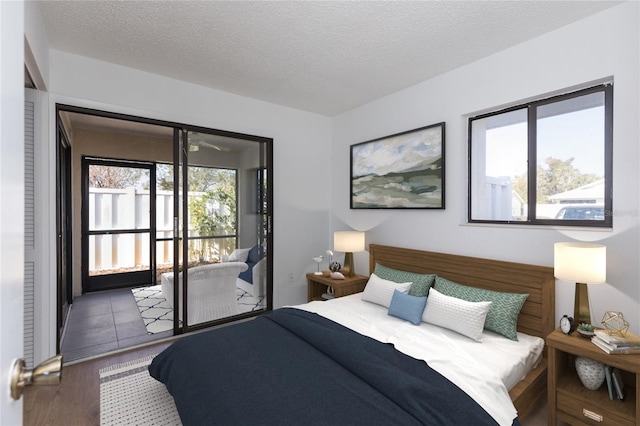 bedroom with hardwood / wood-style flooring, access to outside, and a textured ceiling