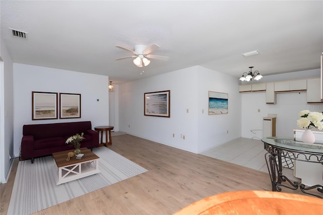 living room with ceiling fan with notable chandelier and light hardwood / wood-style floors