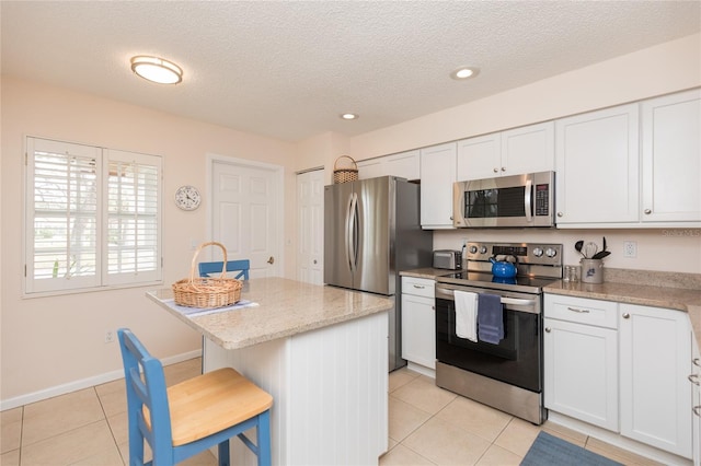 kitchen with white cabinetry, appliances with stainless steel finishes, a kitchen breakfast bar, and a kitchen island